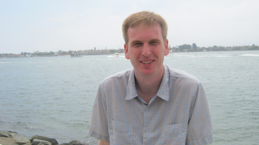 Justin Smith from Vancouver BC on vacation in San Diego sitting on a wall next to San Diego Bay.