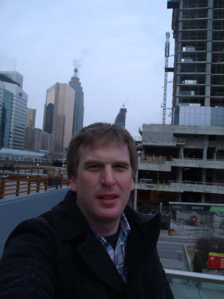 Justin Smith standing in downtown Toronto with high rise buildings in the background. 