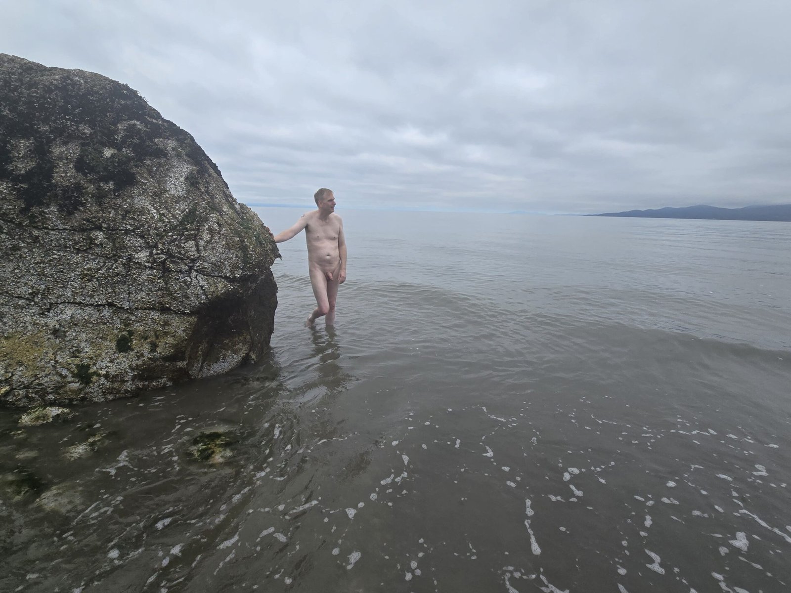 man standing naked at Wreck Beach a clothing optional beach in Vancouver.