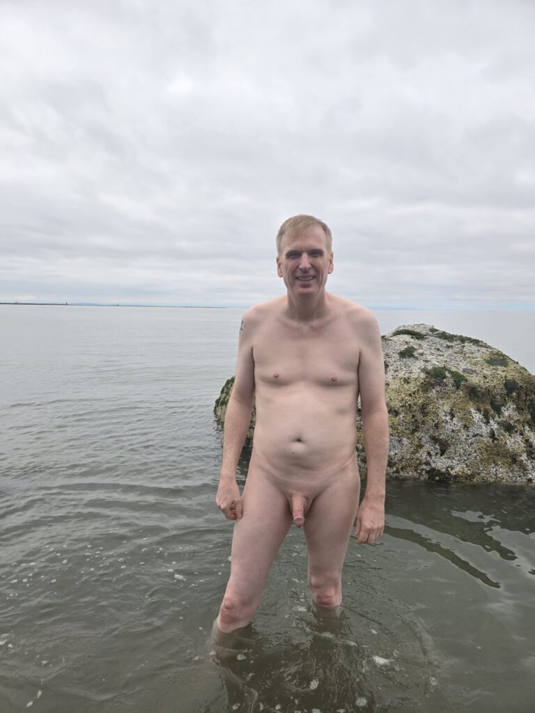 man standing naked on the beach.