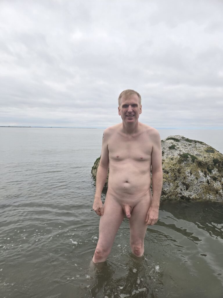 Nude male standing in the water at Wreck Beach in Vancouver, a clothing optional urban beach. 