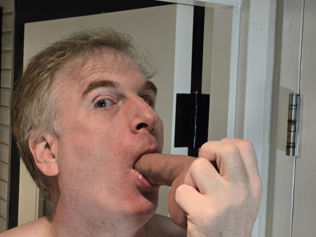 headshot of a male sucking a dildo.