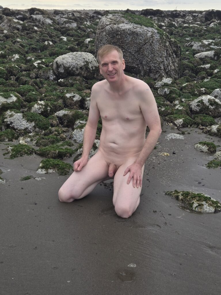 Man kneeling naked at Wreck Beach.