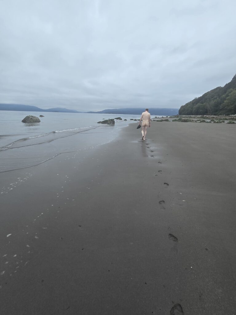 Man walking down the beach on a cloudy day.